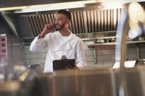 Restaurant chef holding clipboard talking on phone