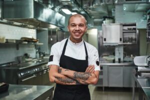 Smiling chef stands in restaurant kitchen